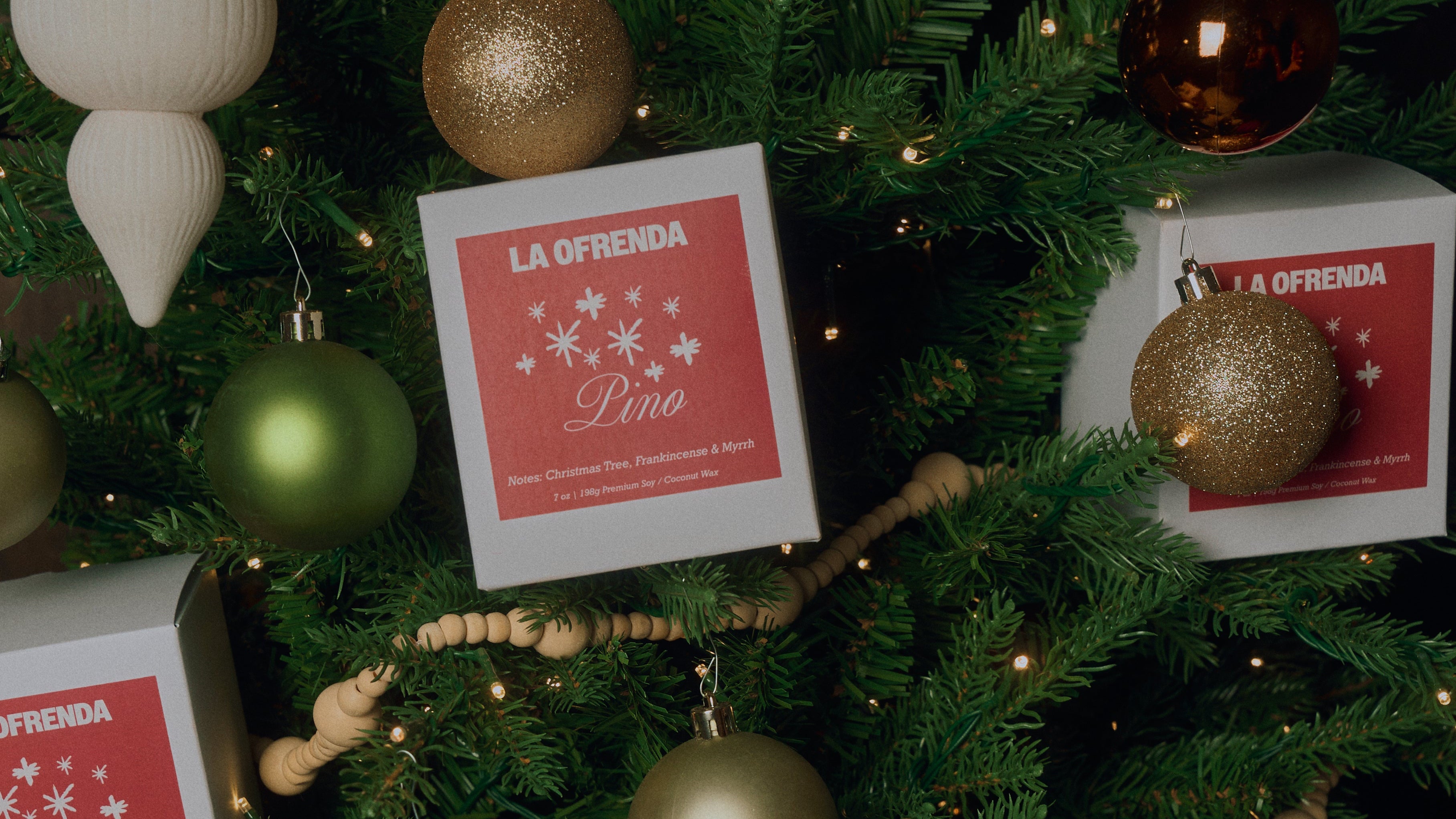 Decorated Christmas tree with ornaments and 'La Ofrenda' boxes.